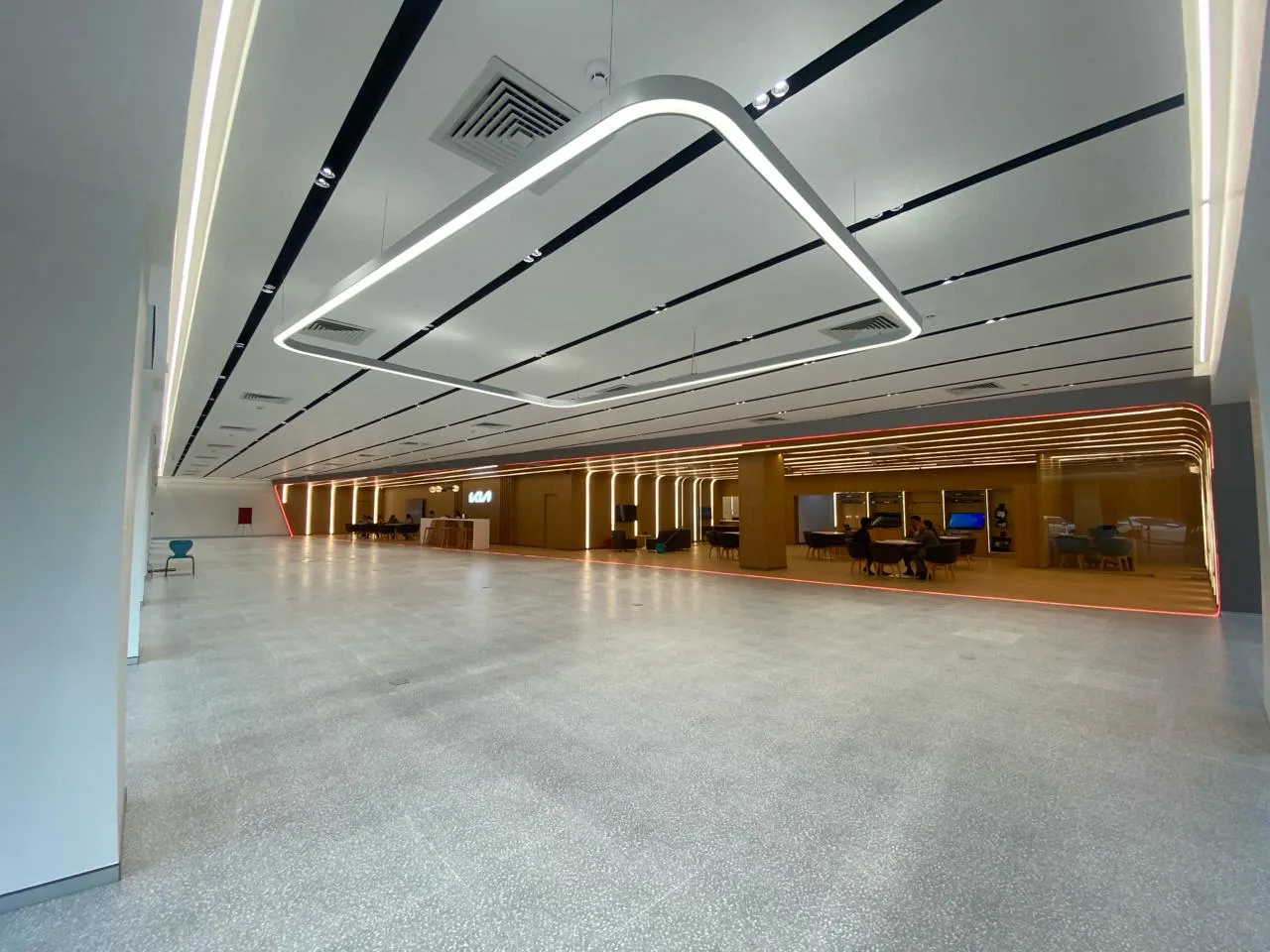Main vehicle display floor with grey microconcrete flooring, minimalist white walls, and linear LED tracks suspended from a black ceiling.