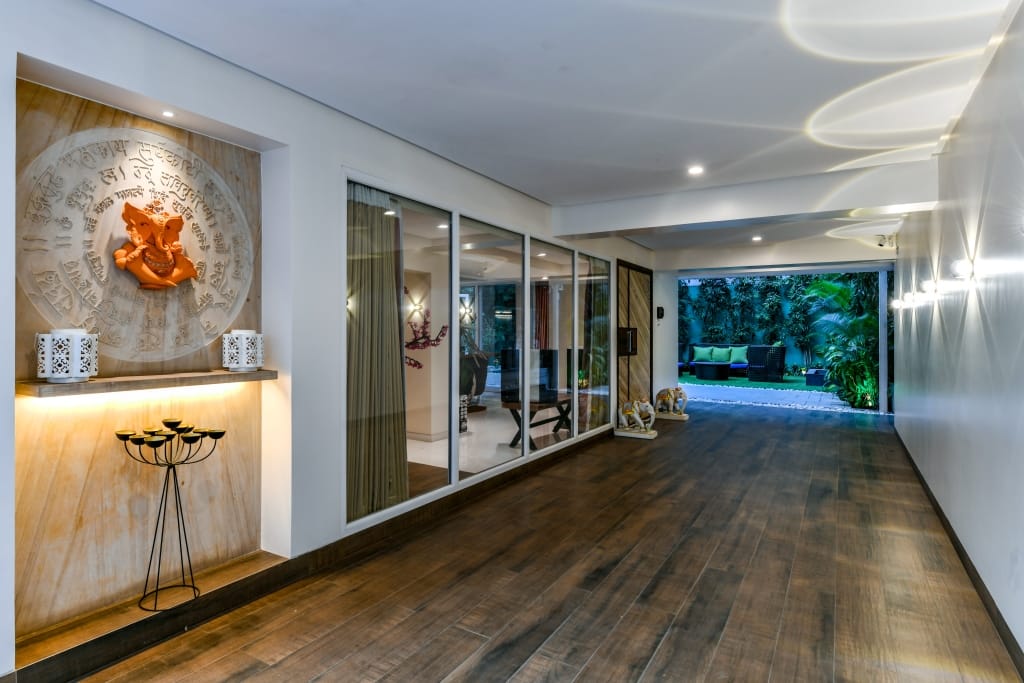 Double-height entrance foyer with a sleek black console table, large abstract canvas art, and polished granite floors with brass strips.